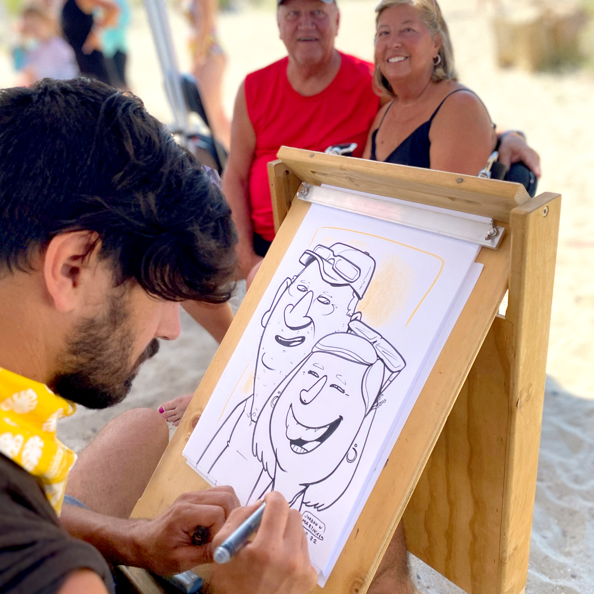 A couple sitting to get their caricature done at a beach summer party