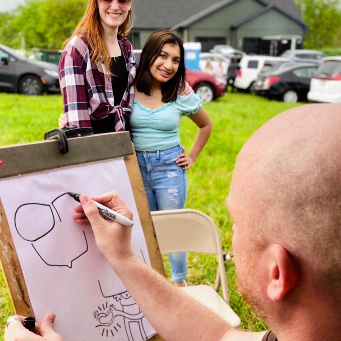A caricature artist drawing two girls at a summer picnic