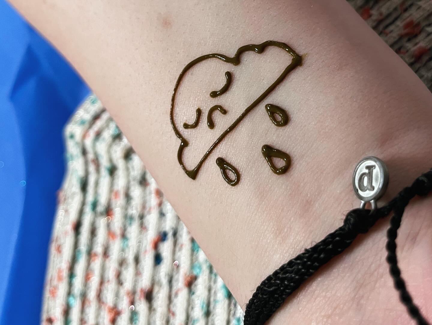 A sad rain cloud henna tattoo on the wrist