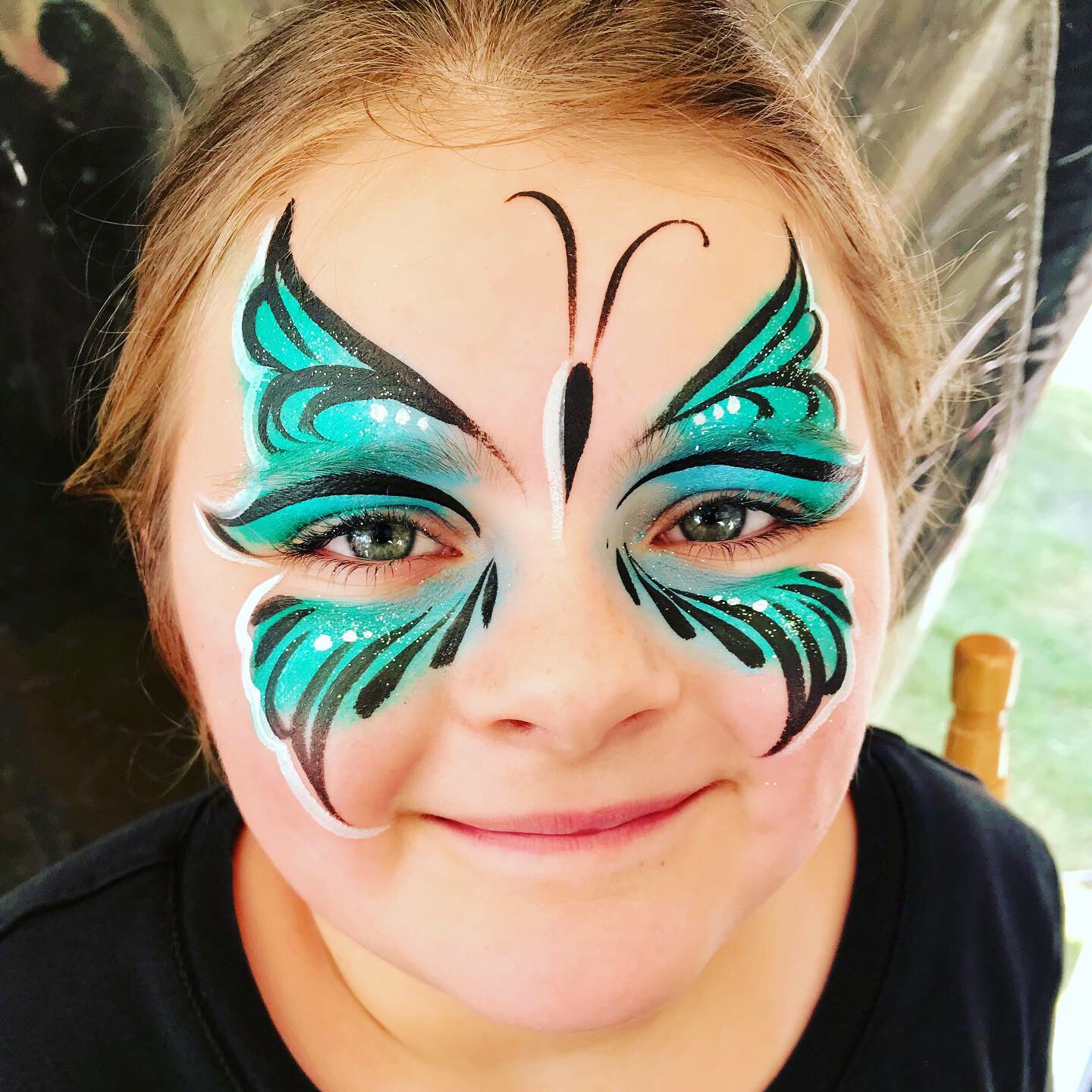 A teal butterfly face paint