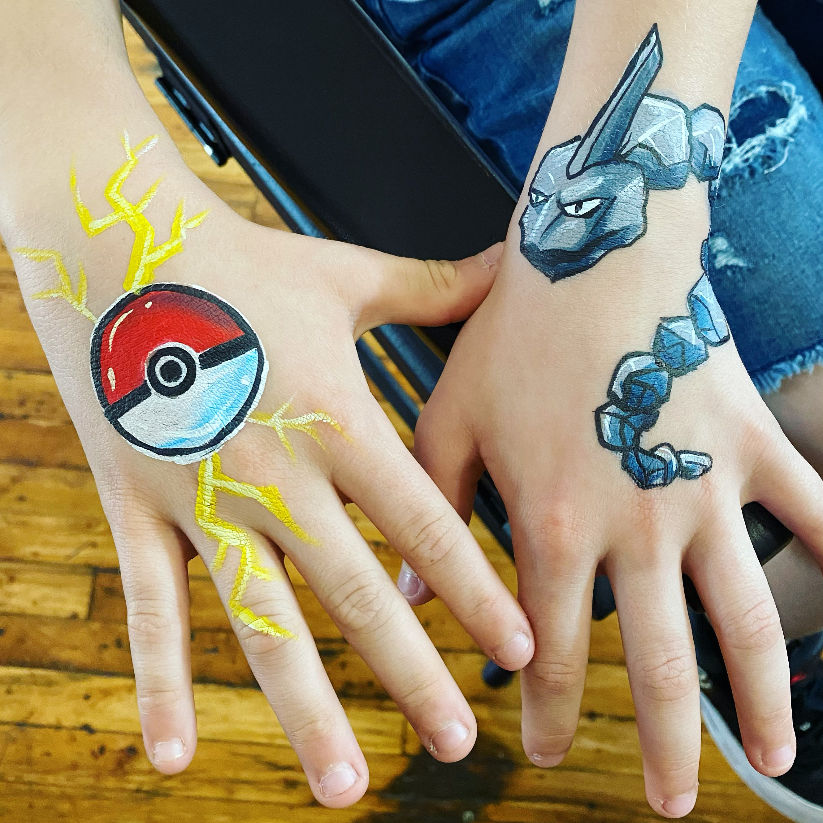 A pokeball and pokemon face paintings on the hands
