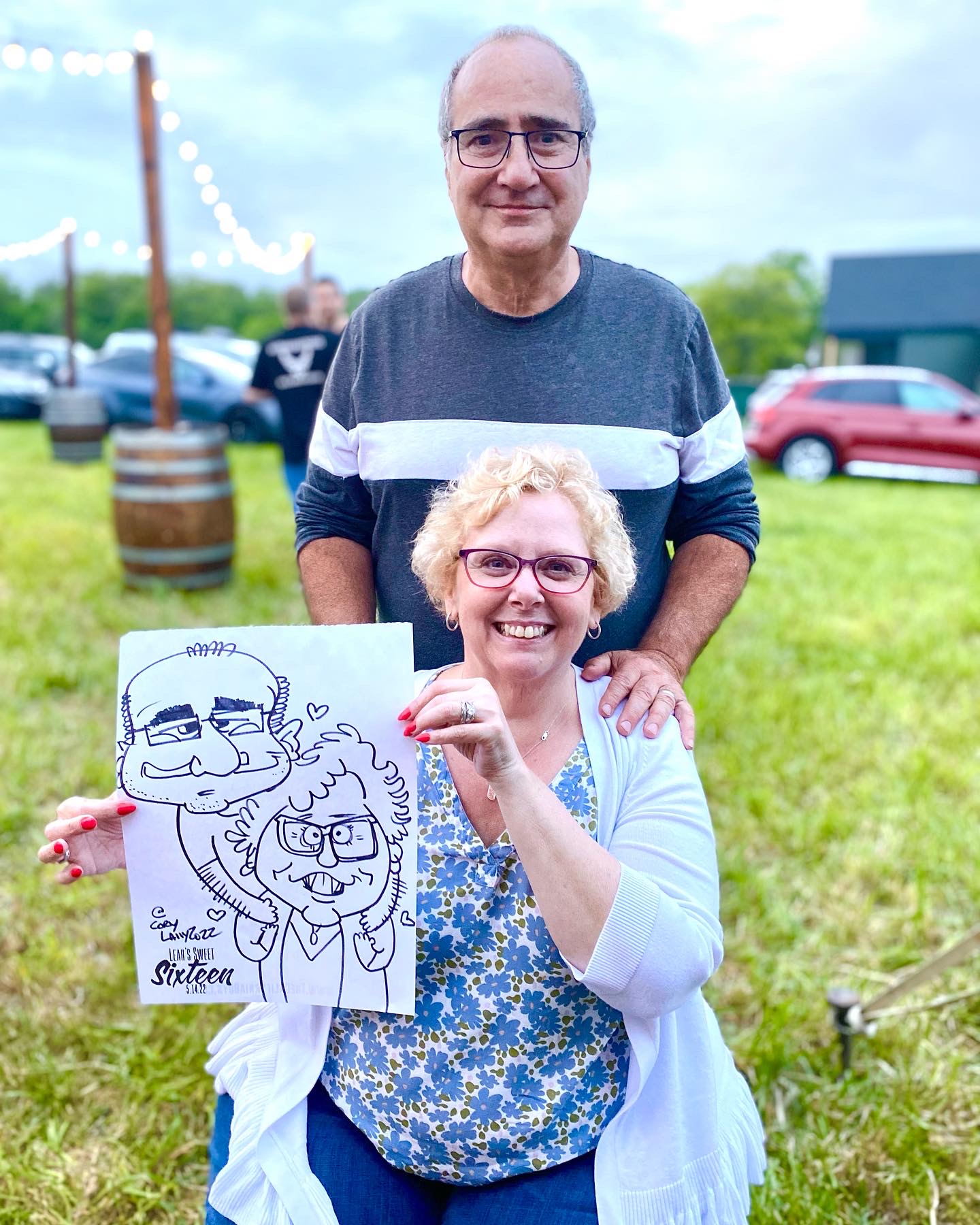A couple holding their caricature at a birthday party