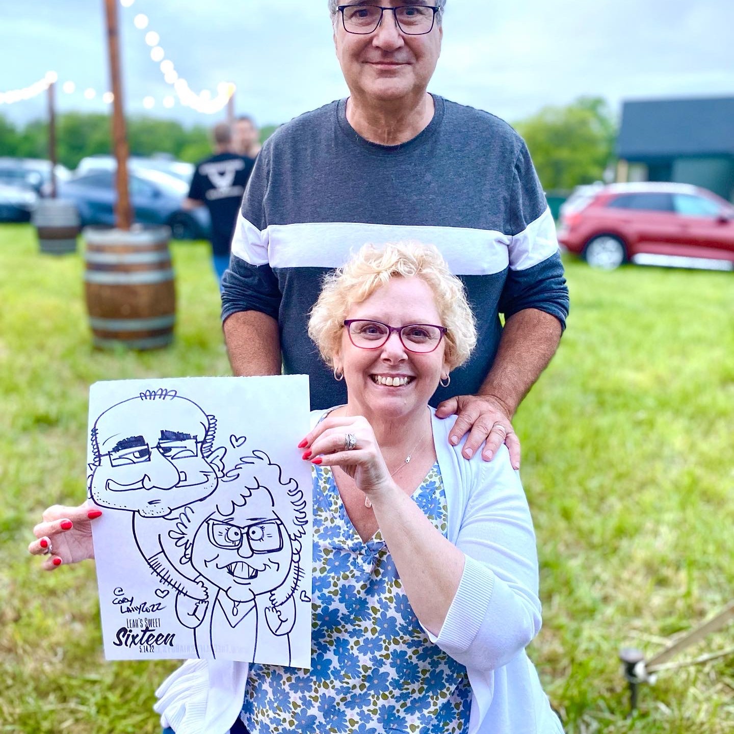 A couple holding their caricature at a birthday party