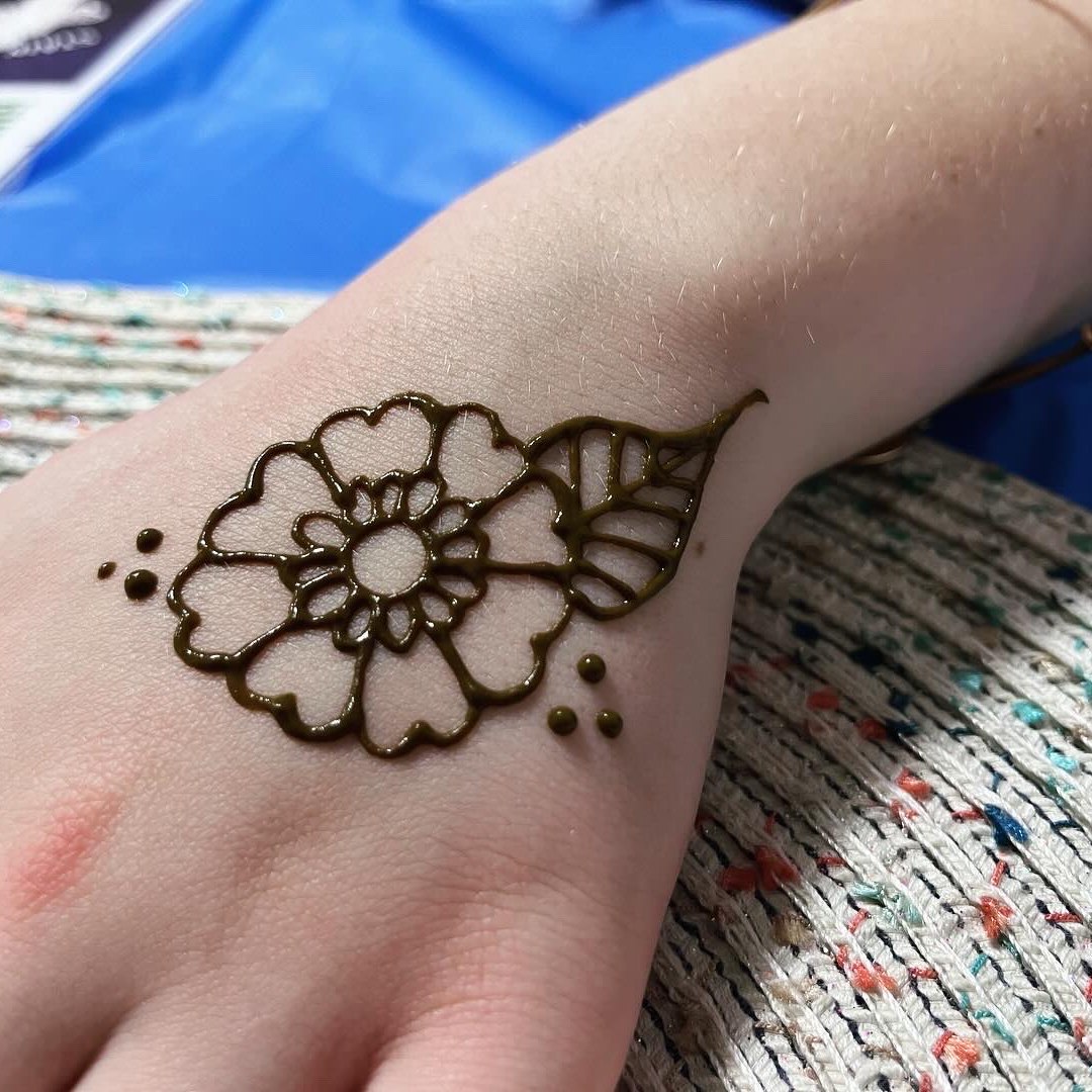 A marigold henna tattoo on the back of the hand
