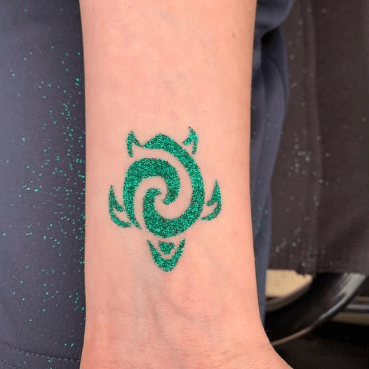 A sparkly green swirly turtle glitter tattoo at the beach