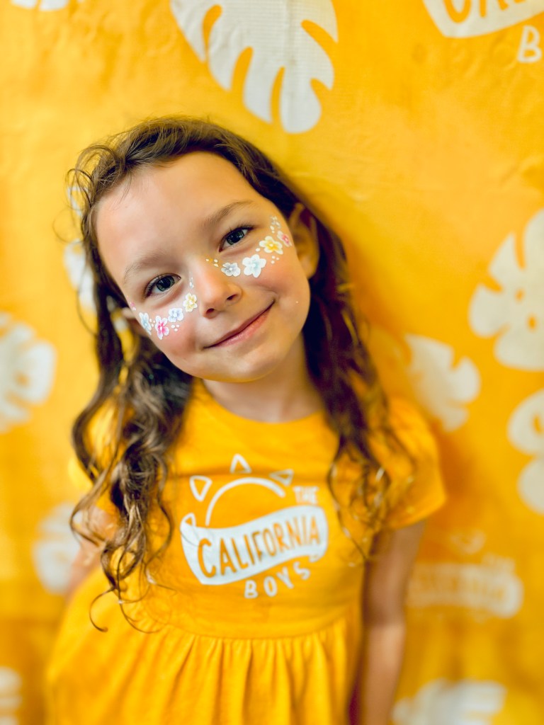 A little girl with her face painted with flower freckles