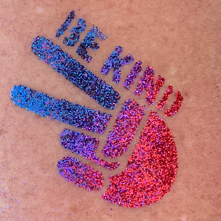 A glitter tattoo of a hand doing the peace sign with the words "Be Kind" above it