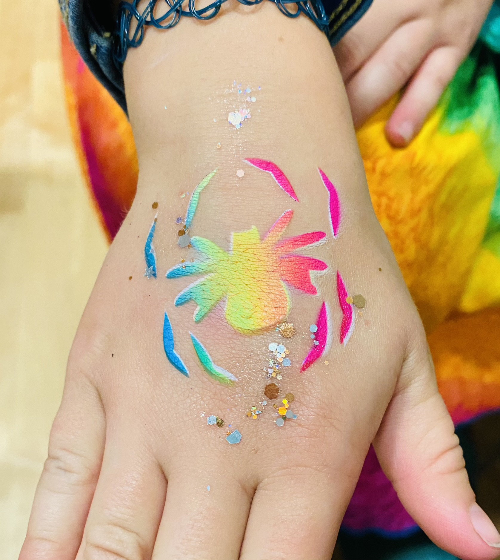 A rainbow spider airbrush tattoo on the arm at a school event