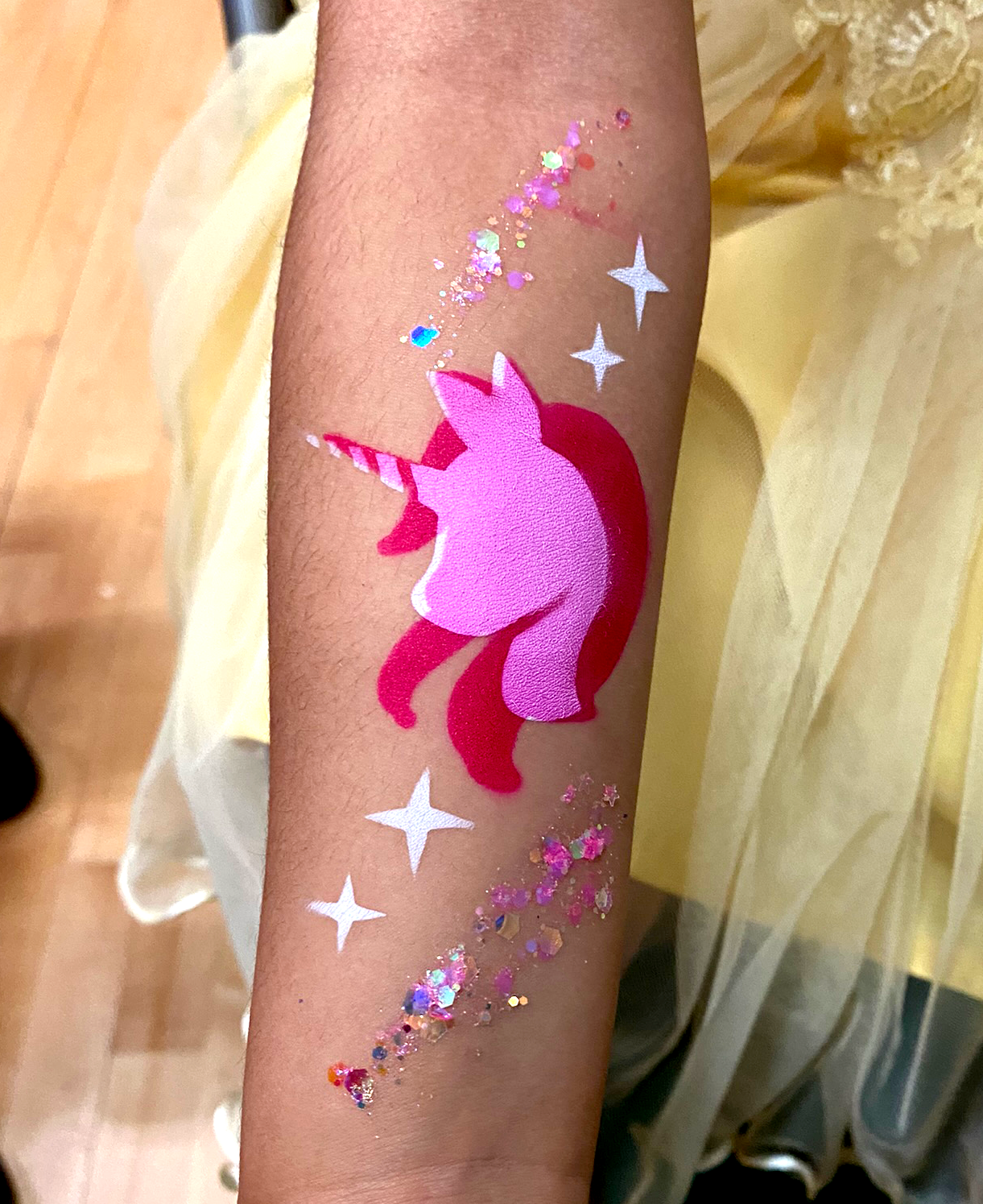 A pink unicorn airbrush tattoo on the arm at a school event
