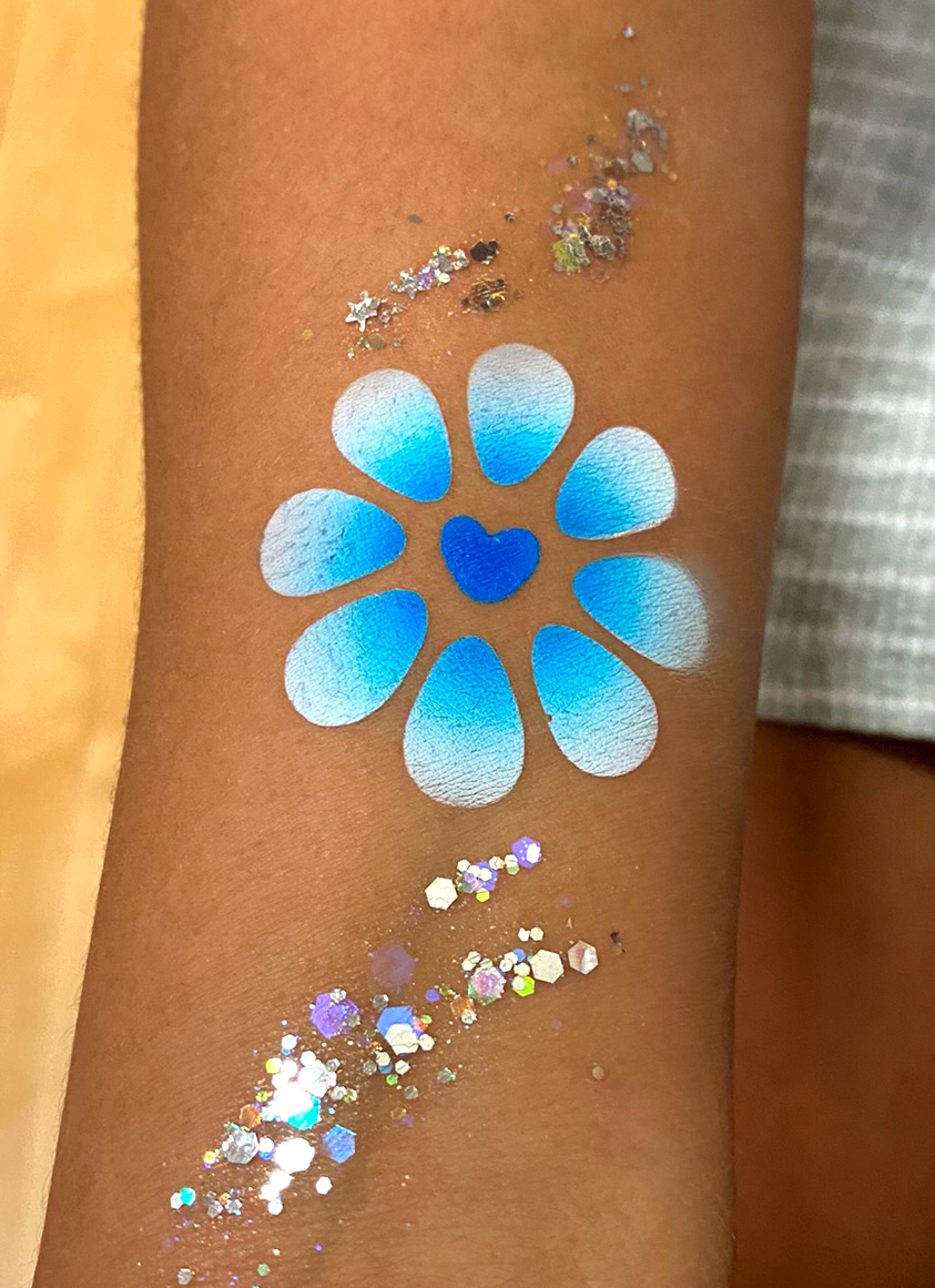 A blue and white flower airbrush tattoo on the arm at a school event