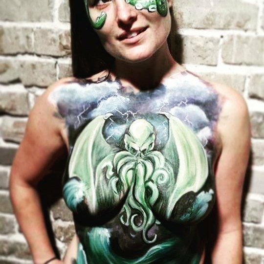 A Cthulhu themed body paint on a model in front of a brick wall
