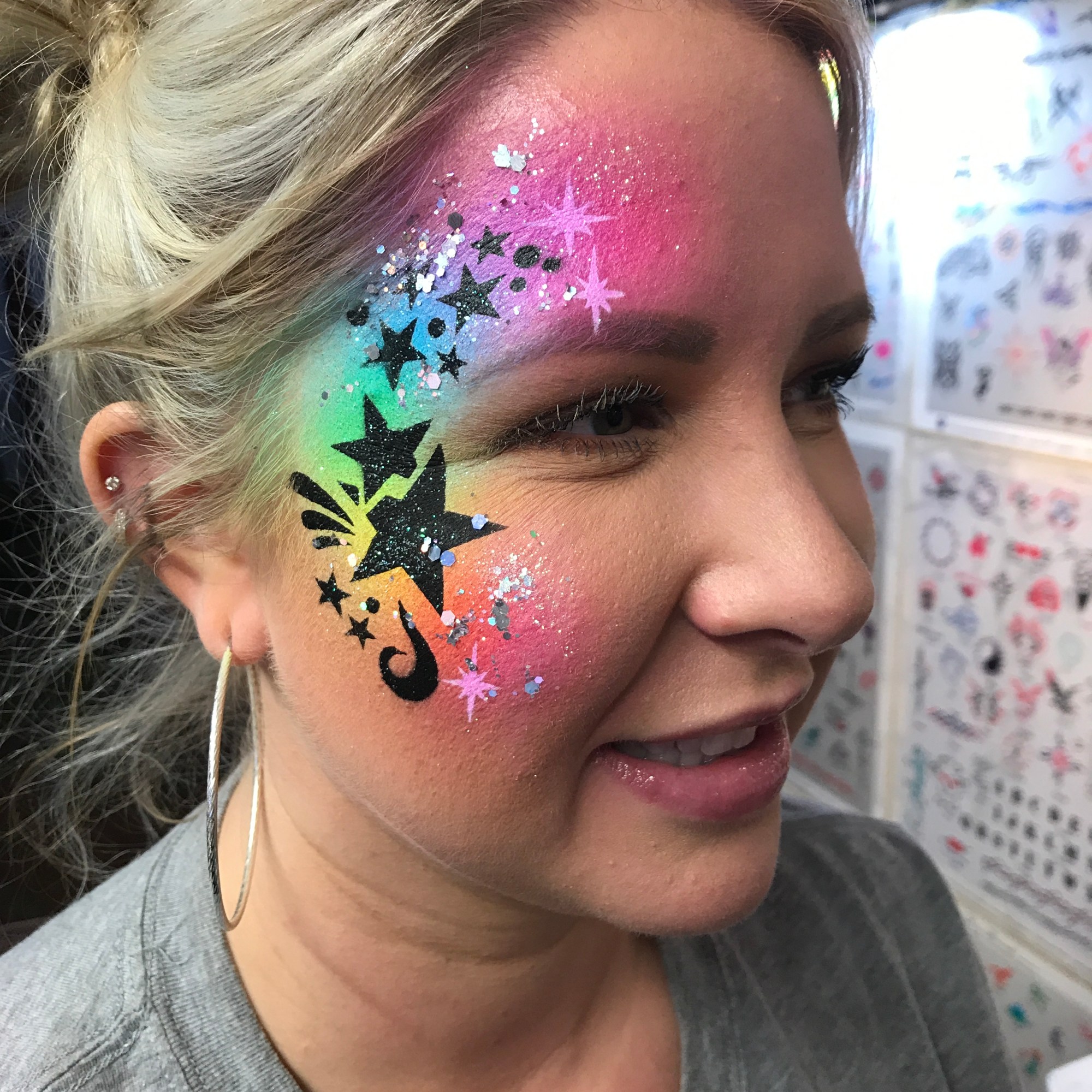 A rainbow star themed airbrush face paint
