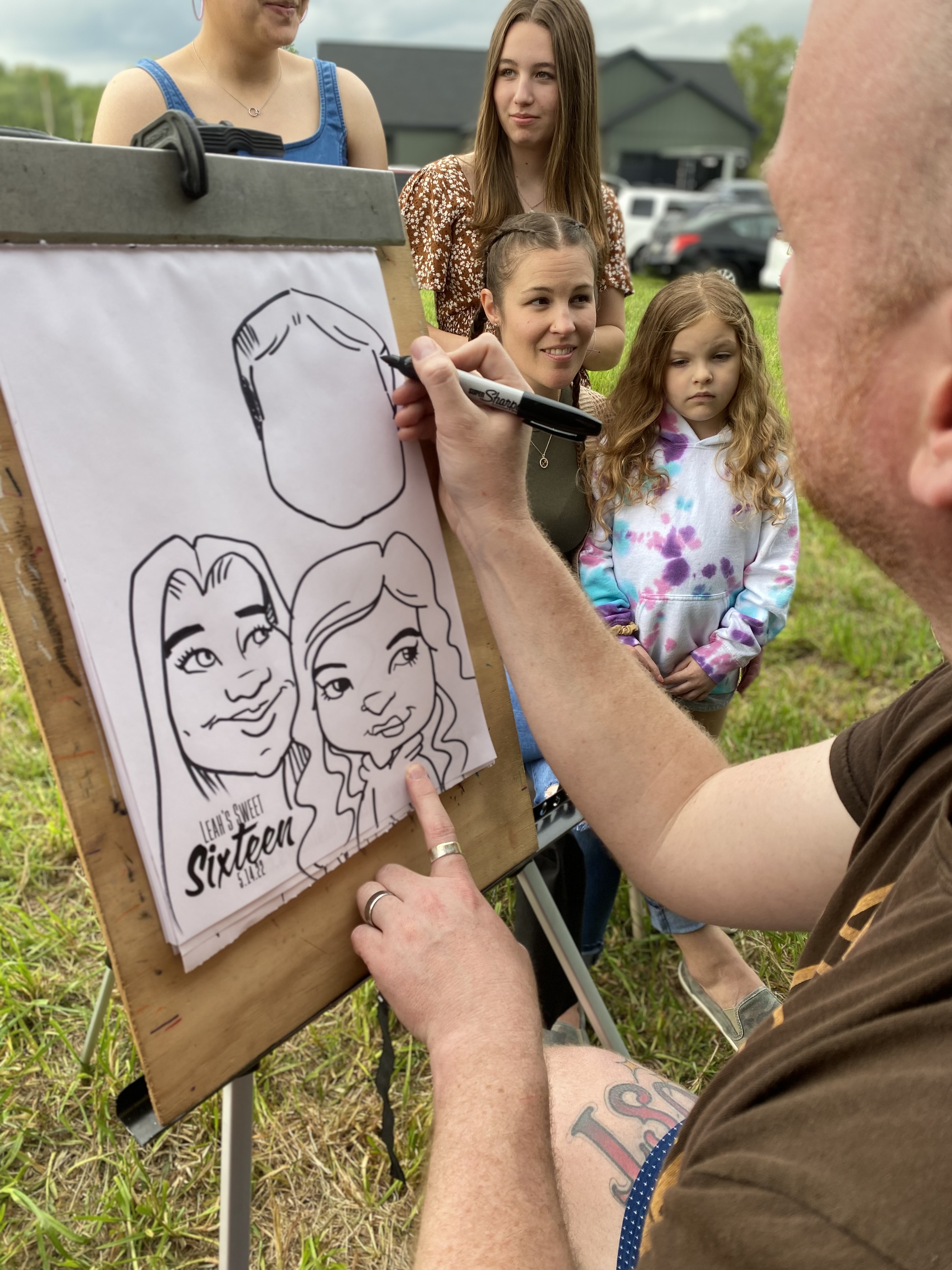 A group of girls posing for a caricature artist at a wedding reception