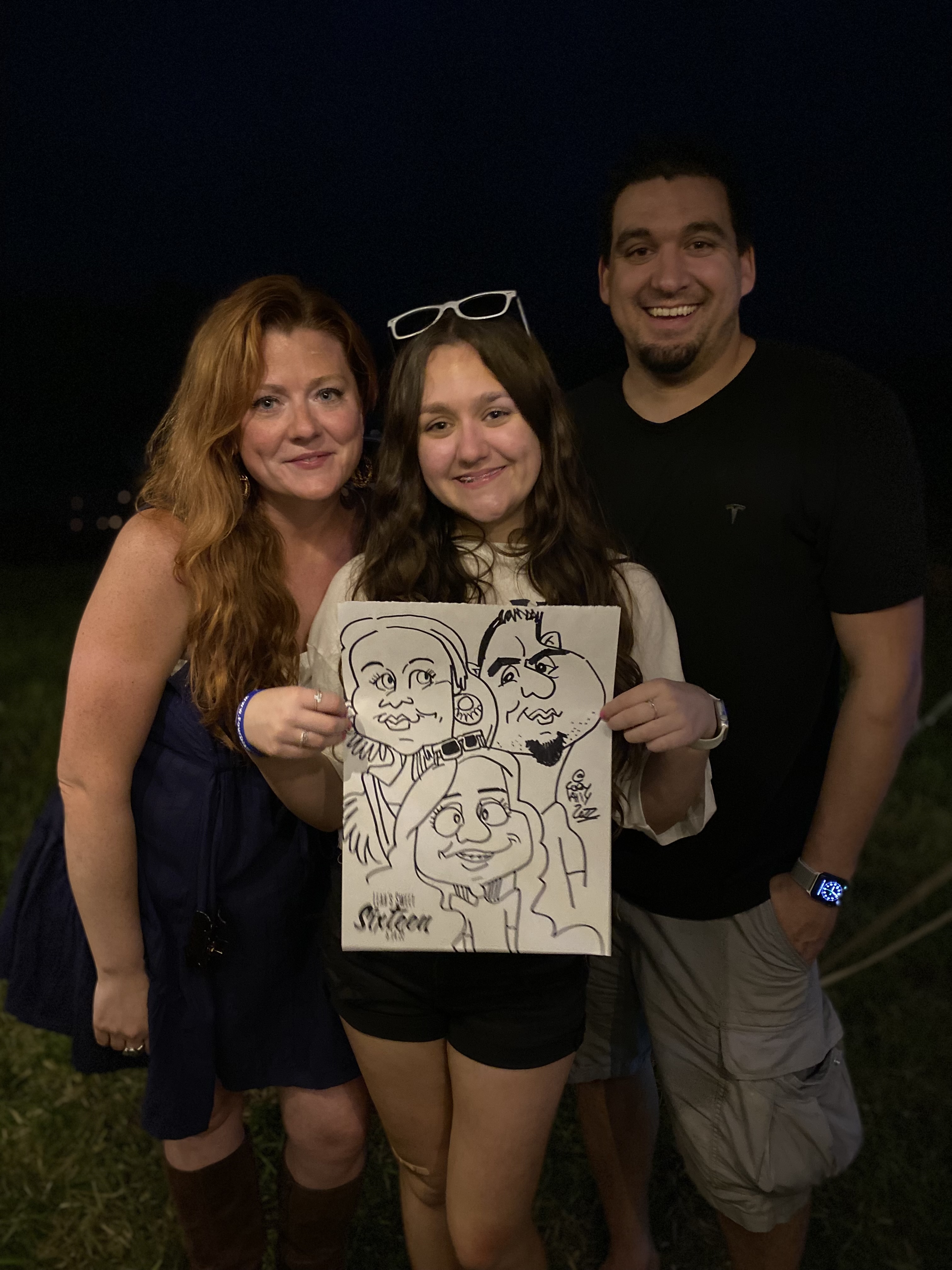 A family of 3 holding a black and white caricature of themselves