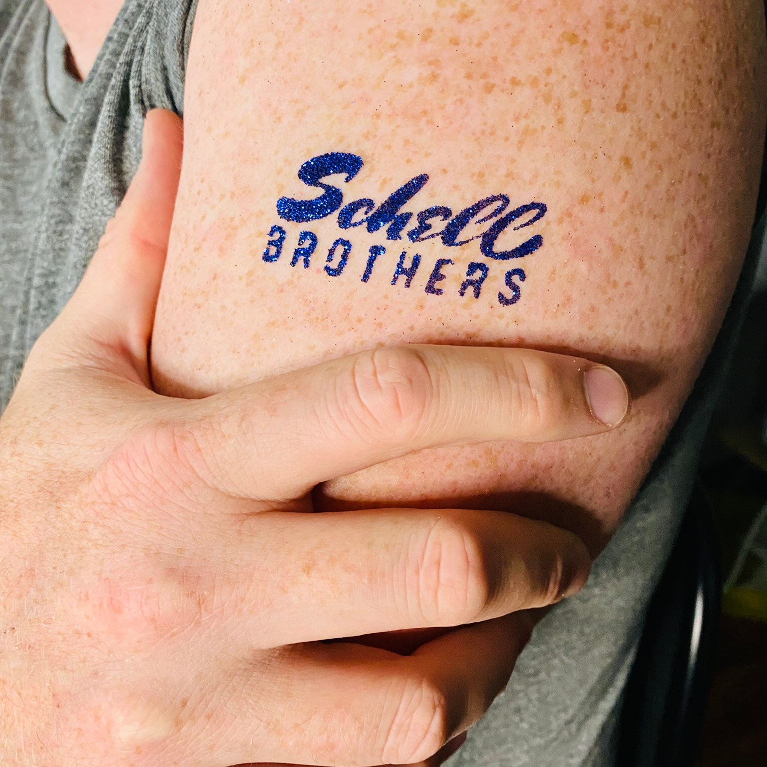 A custom sparkly navy blue Schell Brothers glitter tattoo