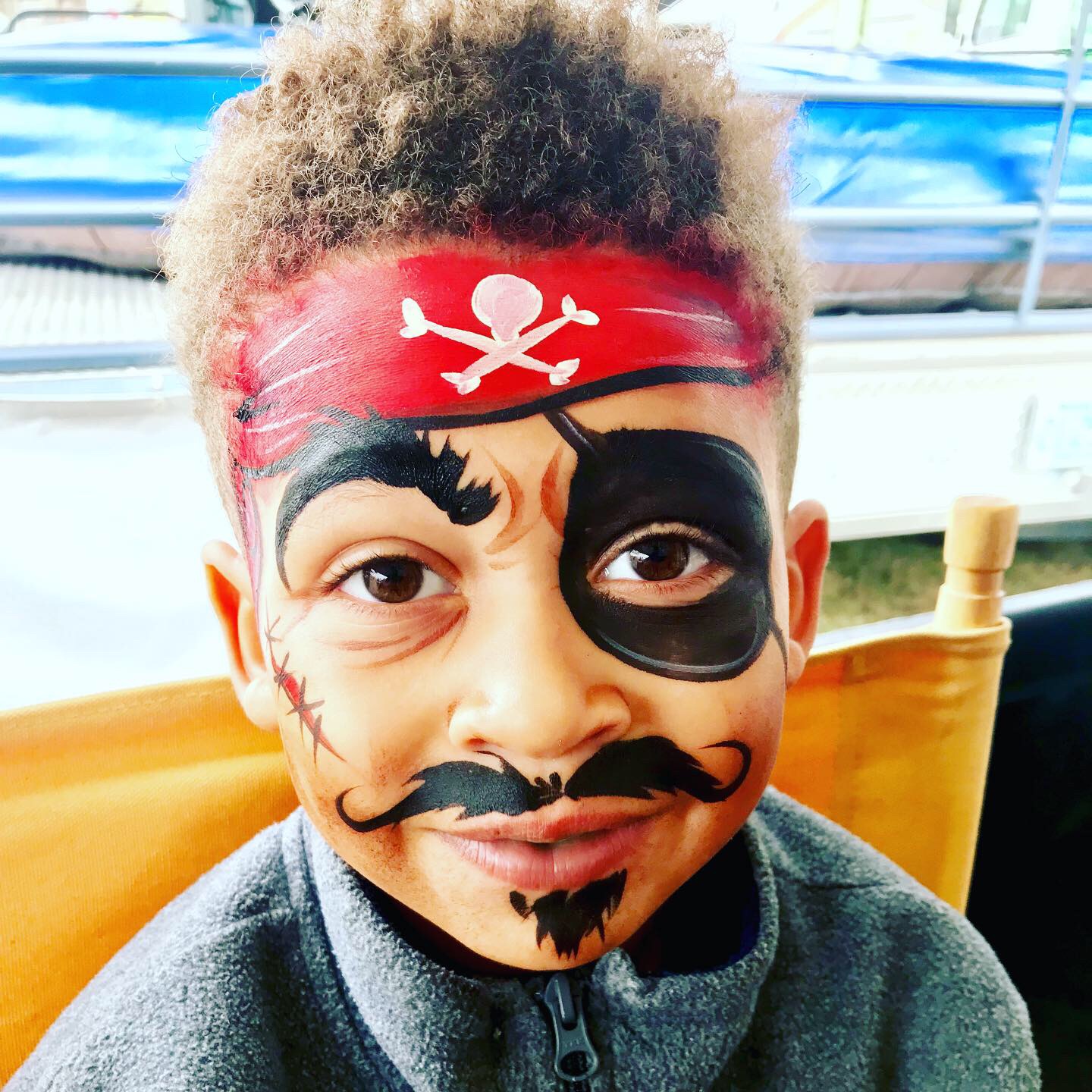 A pirate face paint on a little boy with curly hair