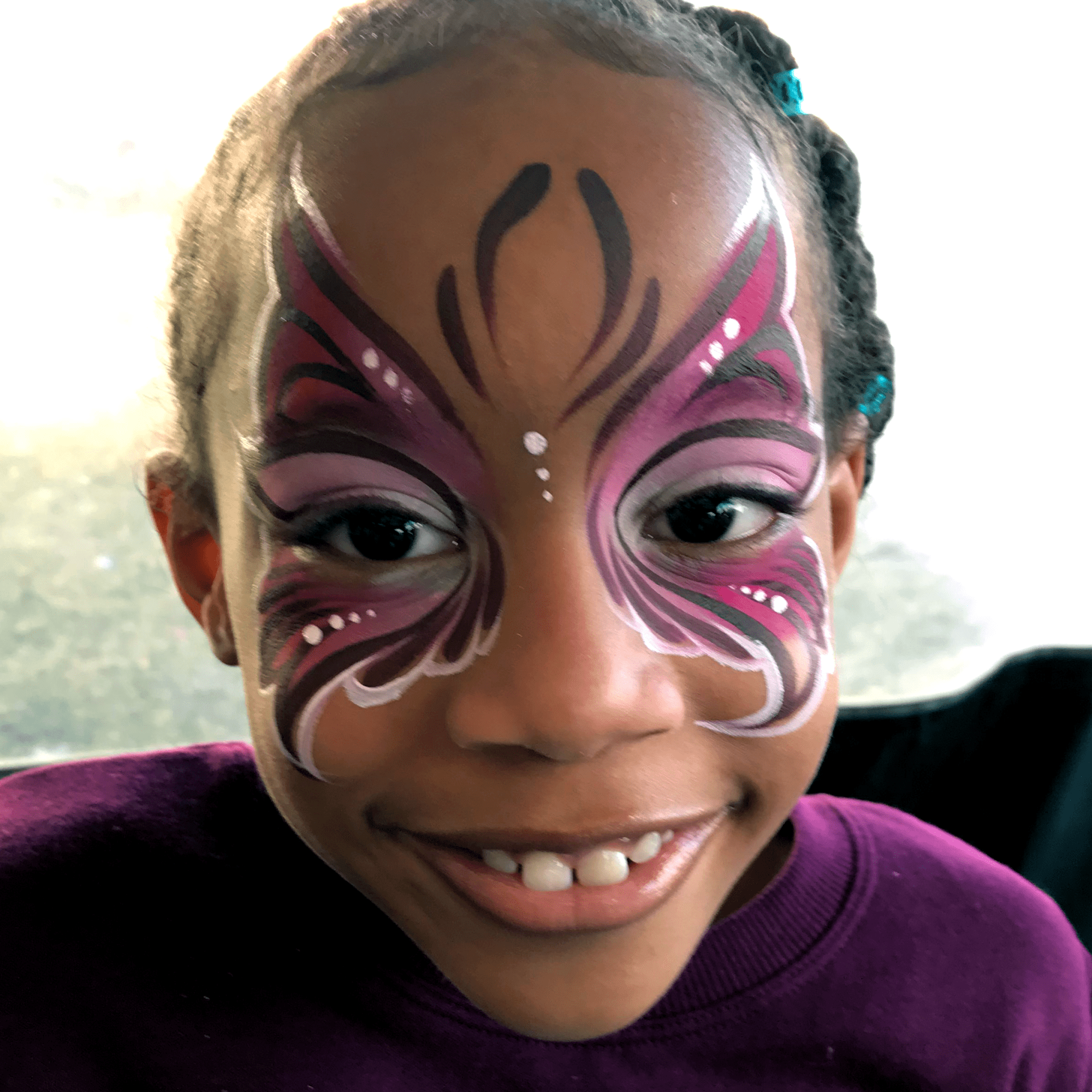 A purple and pink fairy face paint on a little girl