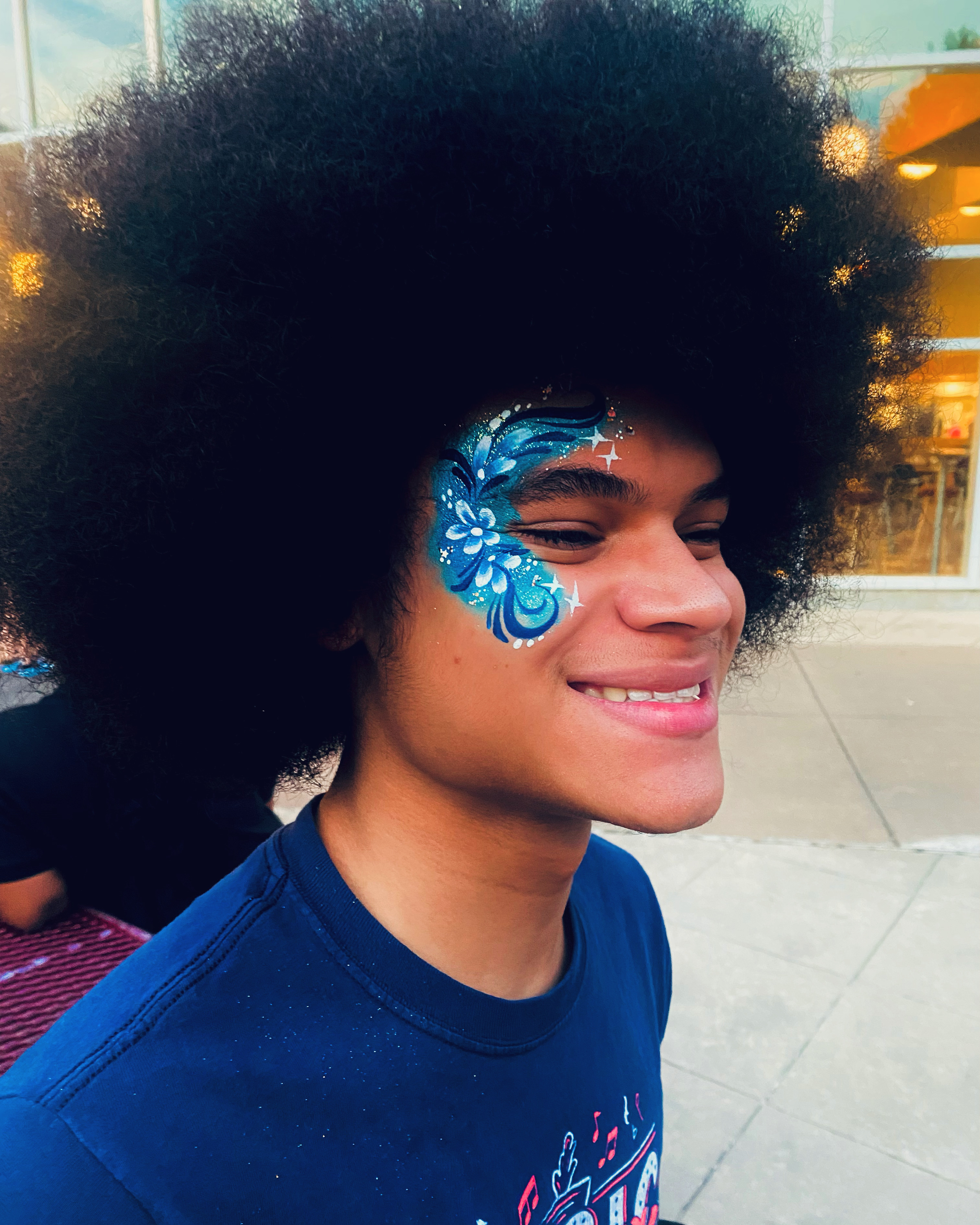 A bright blue flower design on a young man with a large afro
