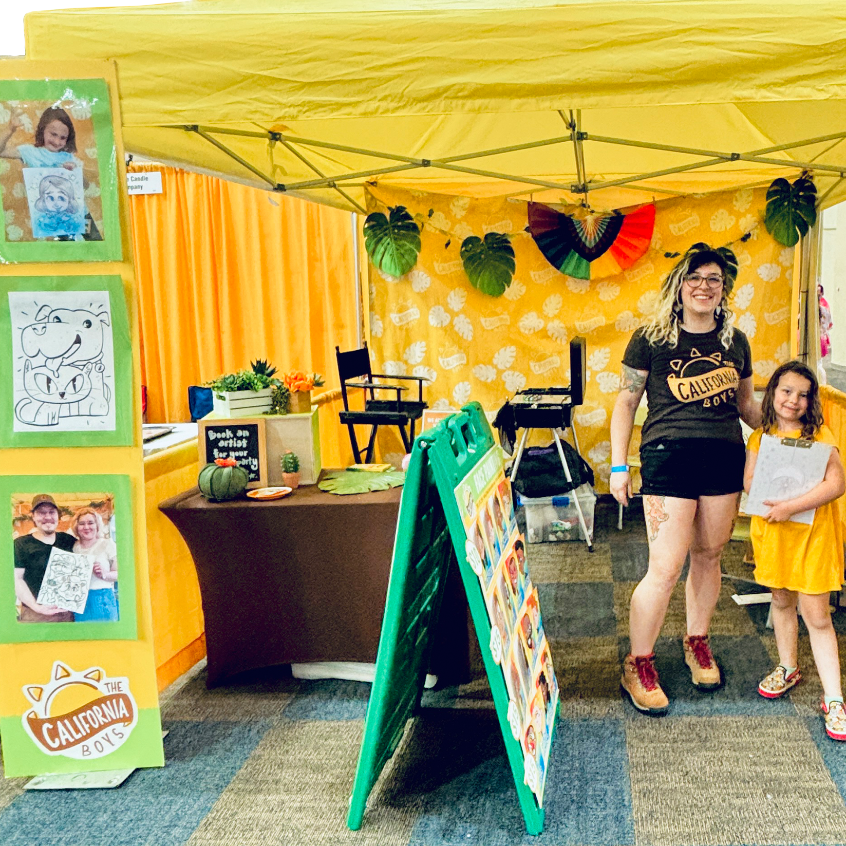 2 caricature artists standing in The California Boys tent selling face painting and caricatures