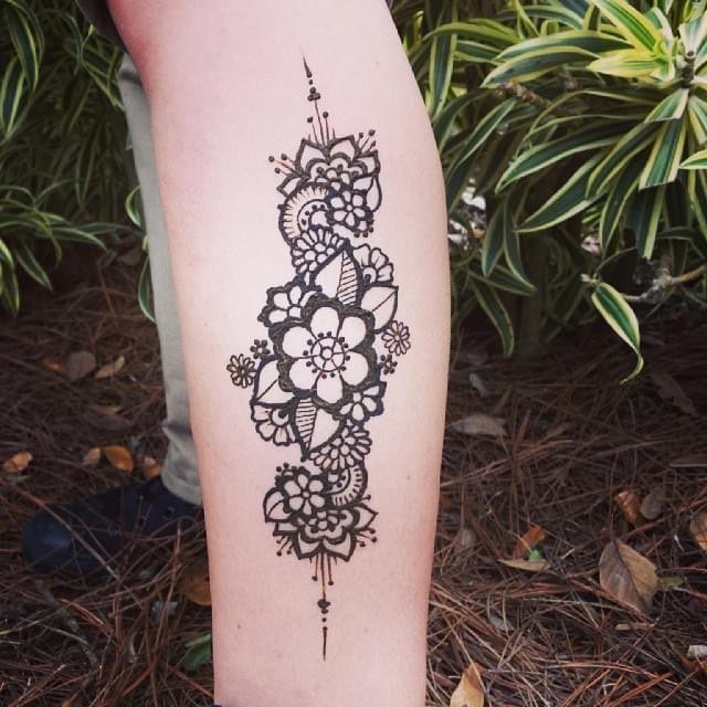 A tropical floral henna design on a leg