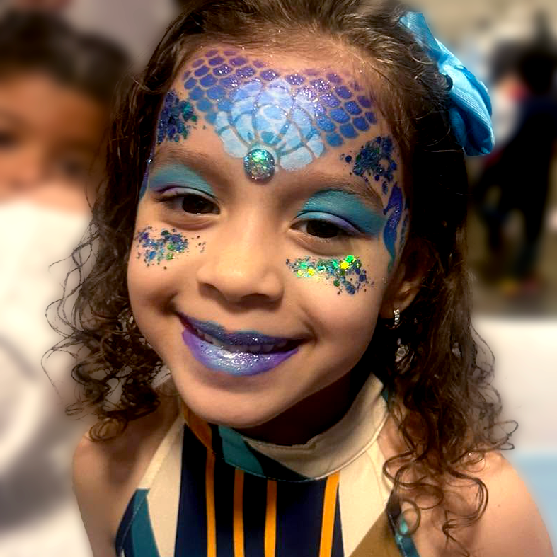 A mermaid face paint using stencils and chunky glitter.