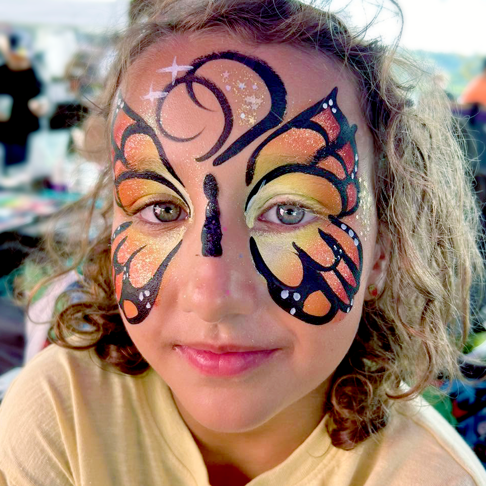 A vibrant Monarch butterfly face paint mask.