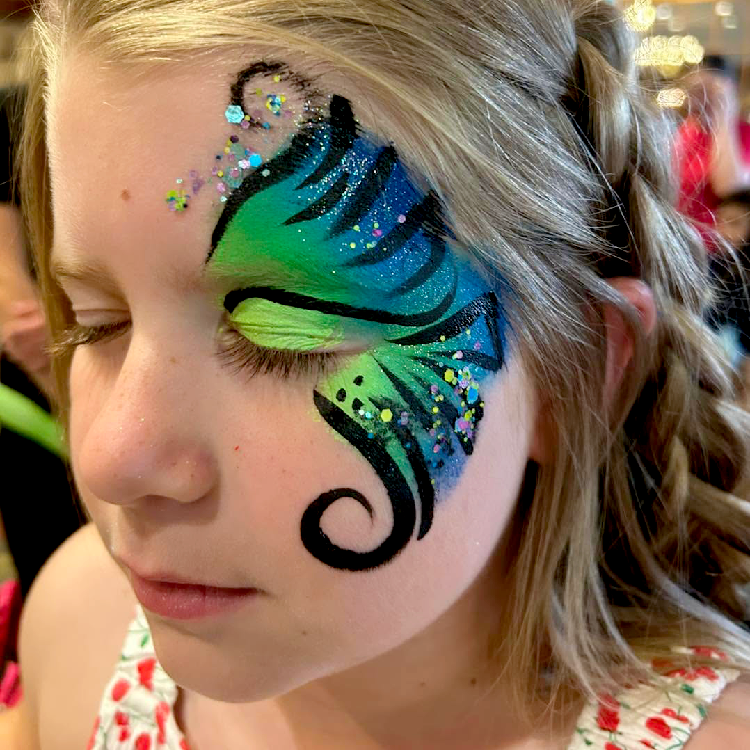 A face paint on one eye of blue and green swirls.
